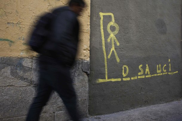 DOCU_GRUPO A man walks past a drawing of a hangman with the word eviction spelled out, on a street in central Madrid_desahucio